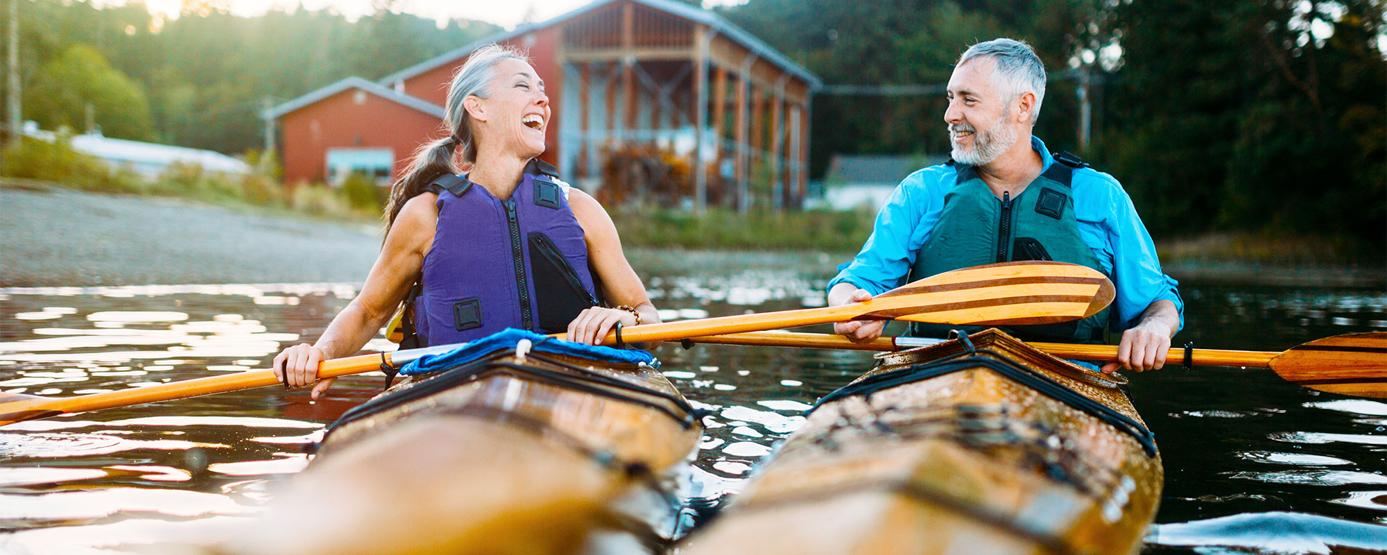 A man and woman laughing while kayaking.